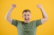 © Serhii - Excited young man guy posing isolated on yellow background studio portrait. People lifestyle concept. Mock up copy space. Rising hands, clenching fists like winner
