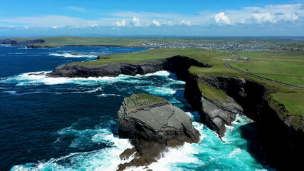 Ireland nature rock stone atlantic ocean water waves foam stream green grass town background blue sky white clouds breathtaking picture shot by drone irish environment coastline travel top view