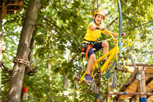 Adorable Little Girl Enjoying Her Time In Climbing Adventure Park On Warm And Sunny Summer Day