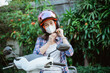 Asian girl with mask tying up helmet safety strap