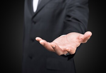 Wall Mural - Male hand in a suit shows a palm up gesture on a background.