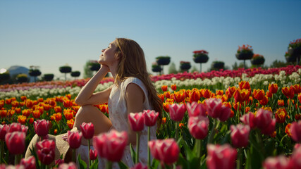 Young woman smiling in bright flower garden. Woman profile in flower background.