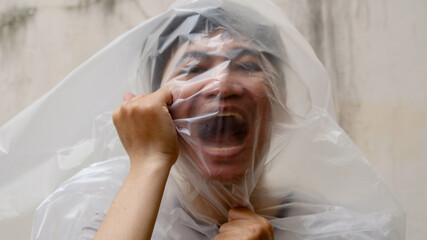 Young Man with a black transparent bag on his head. suffocate. face in a plastic bag, strangulation. 
environmental pollution