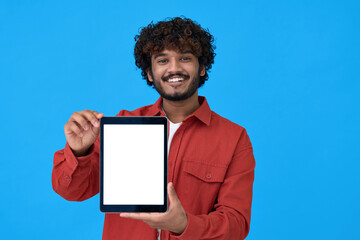 Happy young indian man holding tablet computer showing big mockup white blank empty template screen isolated on blue background advertising website presenting offer or application ads concept.