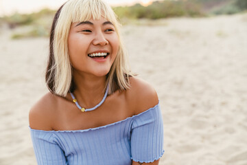 Wall Mural - Young asian woman laughing while resting on beach