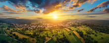 Aerial Panoramic Landscape With A Small Town At A Dramatic Colorful Sunset With Blue Sky And Gold Clouds