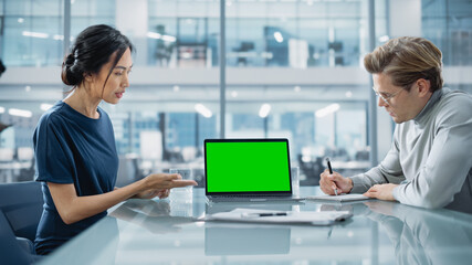 Leinwandbilder - Multiethnic Diverse Office Conference Room Meeting: Team of Two Creative Entrepreneurs Talk, Discuss Growth Strategy, Use Laptop with Green Screen Mock Up Display.