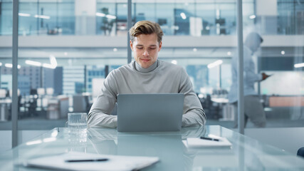 Wall Mural - Successful Handsome Businessman Working on Laptop Computer in Big City Office. Finance Investment Analyst Checking Analytics from Project Management Reports, Answering Emails, Checking Social Media.