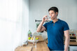 Asian attractive young man stand drinking water and looking out window. 