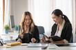 © amnaj - Two beautiful Asian businesswoman talking exchange ideas at work.
