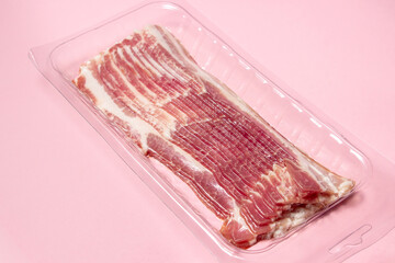 Canvas Print - Vacuum-packed bacon on a pink background. A modern way of storing and selling meat. Pig meat.