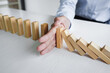 Risk and strategy in business, Close up of business woman hand stopping wooden block between three way from falling in the line of domino