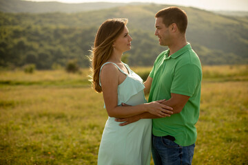 Wall Mural - Young husband and his pregnant wife in the summer field