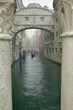 Die Seufzerbrücke in Venedig und ein Gondolieri schifft mit seiner Gondel auf einem Kanal zwischen den Häusern bei Nebelwetter.