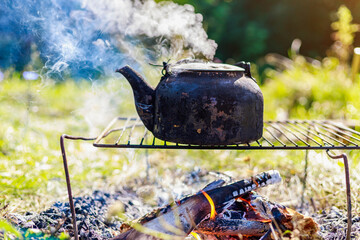 old camping kettle with a black layer of carbon on the fire. Hiking food at the tourist camp. Background