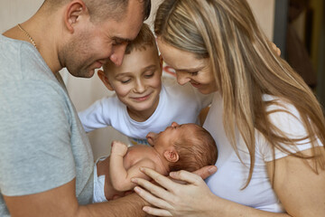 mother, father and daughter are looking at newborn baby