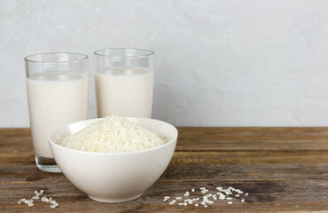 Two glasses with alternative dairy free rice milk and seeds in a bowl on wooden table. Lactose free beverage