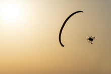 Paramotor Vehicle Tilted Flying In A Yellow Sky By The Sun