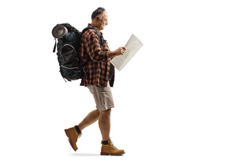 Poster - Full length profile shot of a mature hiker reading a map and walking