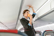 Flight attendant demonstrating how to use oxygen mask in airplane