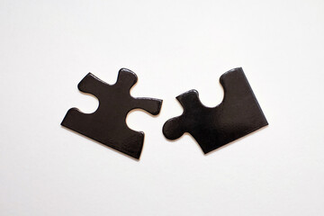 Wall Mural - Two black puzzles on a white background. Puzzle for the development of children's intelligence. The concept of connection in the form of two plates of one whole. Association and connection symbol