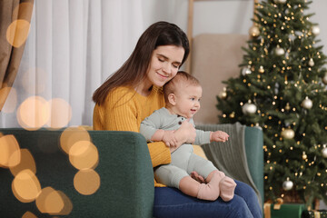 Wall Mural - Happy young mother with her cute baby in room decorated for Christmas. Winter holiday