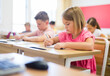 © JackF - Young girls and boys sitting at desks in classroom during lesson.