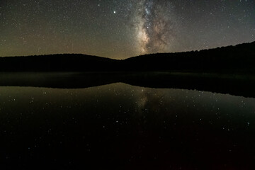Night dark black sky with milky way in Spruce Knob Lake West Virginia water reflection of stars landscape view with brightest star Sirius glowing with Venus planet