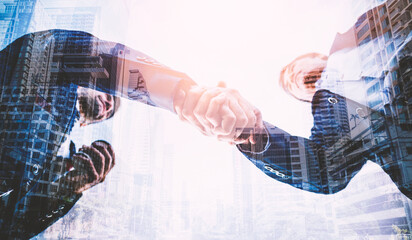 Double exposure of two businessman shaking hands with business deals and congratulations on success.	