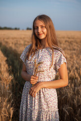 Canvas Print - Portrait of beautiful young girl with a bouquet of spikes. Girl in white dress in the field of rye