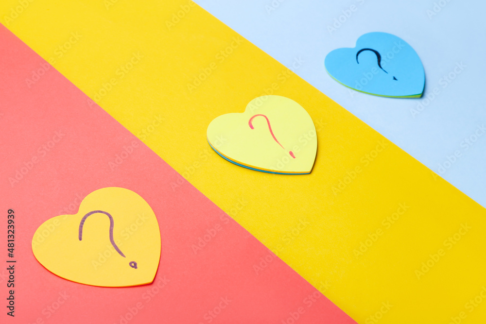 Heart shaped sticky notes with question marks on color background