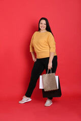 Poster - Beautiful overweight woman with shopping bags on red background