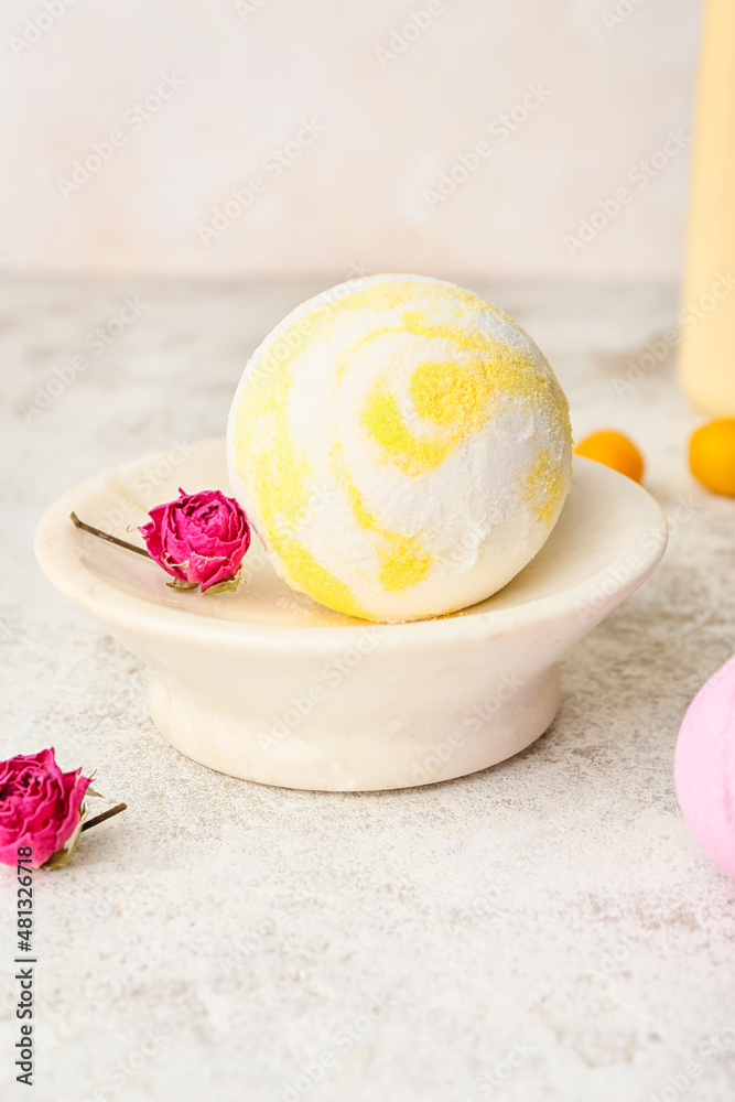 Bowl with bath bomb and dried rose flowers on light background, closeup