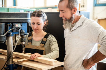 male and female carpenter at work, man and woman are crafting with wood in a workshop