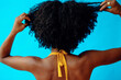 © Carlos David - back shot of a young adult woman with hands on her curly black hair