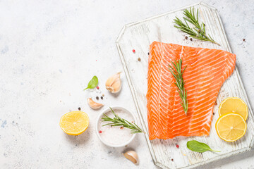 Wall Mural - Salmon fillet with ingredients for cooking - sea salt, garlic and rosemary. Top view at white table with copy space.