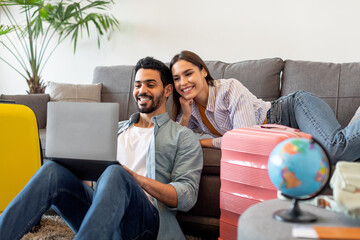 Wall Mural - Happy loving couple planning trip after quarantine, buying low price tickets and booking hotel online, using laptop