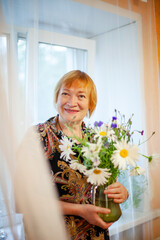 Wall Mural - Old woman with wildflowers at home