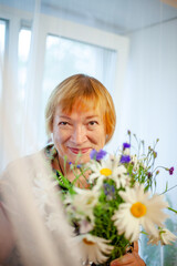 Wall Mural - Old woman with wildflowers at home