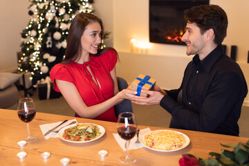 Wall Mural - Young man exchanging gifts with his happy woman