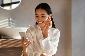 Wall Mural - Attractive young asian woman reading beauty blog online, using smartphone