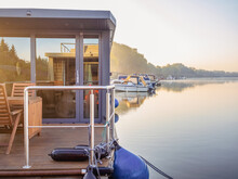 Houseboat On A River In A Early Sunny Morning. Floating House Is A Pleasant Place For Rent For Weekend