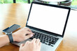 © Thaspol - Mockup image of a businesswoman using laptop with blank white desktop screen with coffee cup on wooden table in cafe..