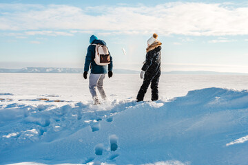 Canvas Print - A man and a little girl walk along a frozen river on a sunny winter day