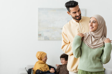 Poster - happy arabian man embracing muslim wife near blurred multiethnic family.