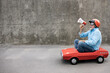 © Sunny studio - Funny businessman driving retro pedal car outdoor