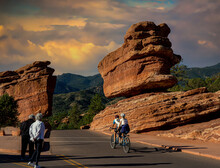 Colorado Springs - 9-19-2021: Two People Ona Two Seat Bicycle Riding Past Balancing Rock At The Garden Of The Gods Near Colorado Springs Colorado