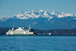 A ferry boat moves on Puget Sound with snow-capped Olympic mountains in the background on a winter day in Seattle, WA
