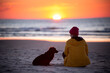 Dziewczyna i pies siedzą na plaży 
