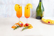 Glass with mimosa cocktail with orange and champagne decorated with strawberries, orange peel, leaves and currants inside the glass on a light background, horizontal position